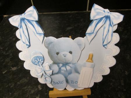 Little Blue Teddy with Bottle and Rattle on Frilly Bib by Anne-marie Wheeler