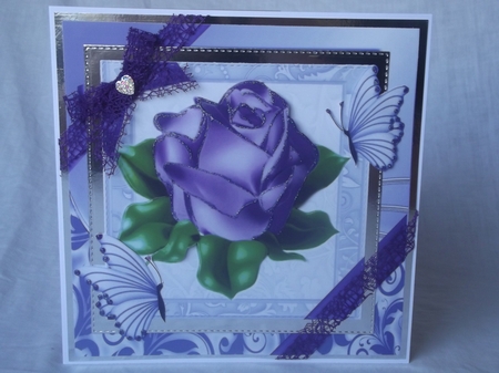 A single pretty purple rose with corner bow in ornate frame 8x8 by Gwyneth Morley