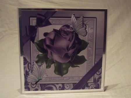 A single pretty purple rose with corner bow in ornate frame 8x8 by Gwyneth Morley