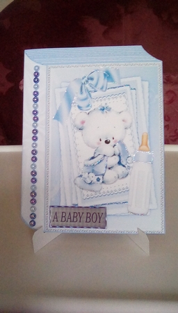 Cute little white bear with blue bow and  bottle on stacker and lace folded book by Joyce Edwards