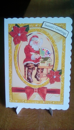 Santa in his workshop with bow and holly card front A5 by Joyce Edwards