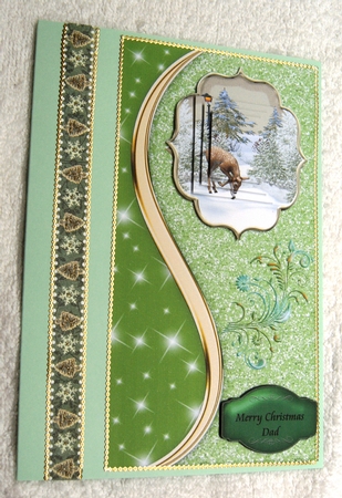 Deer in the snow on a green glitter card front. by Margaret Scott