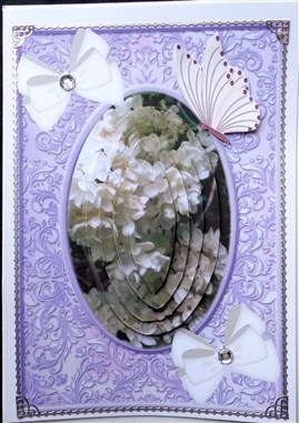 White flowers in purple ornate frame  with bows and butterflies oval pyramids by Mary Murphy
