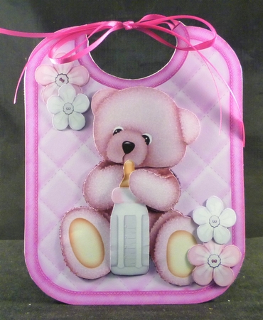 Cute cuddle bear on pink babys bib with bottle by Michelle Chivers