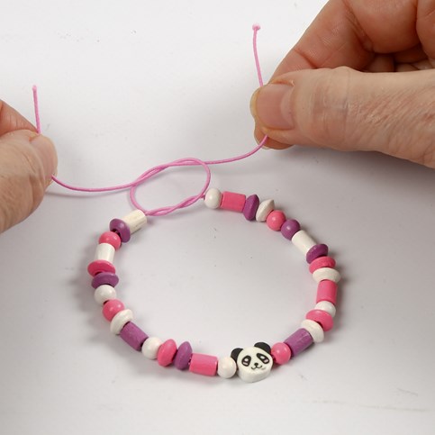 A Bracelet made from coloured Elastic Cord with a Shaped Wooden Bead and Wooden Beads
